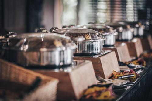 a row of pots and pans on a table with food at Hotel Tieti in Poindimié