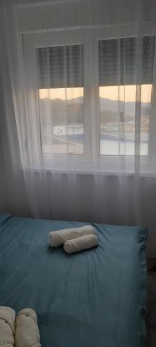 a bed with two pillows on it in front of a window at Apartmani Sunlight in Vrnjačka Banja