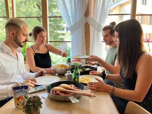 Eine Gruppe von Menschen, die an einem Tisch sitzen und Essen essen. in der Unterkunft Family-Hostel SPANNORT with common kitchen and self check-in in Engelberg