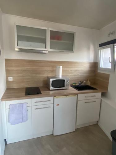 une cuisine avec des placards blancs et un four micro-ondes sur un comptoir dans l'établissement Le Stud' Joli appartement lumineux en plein centre ville, à Cherbourg en Cotentin