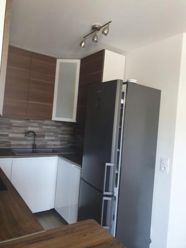 a kitchen with a stainless steel refrigerator and wooden cabinets at Le Baron in Le Blanc-Mesnil