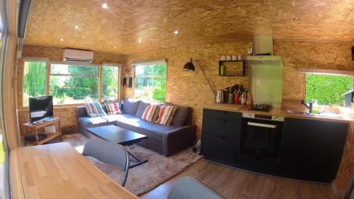 a living room with a couch and a kitchen in a tiny house at Le Cottage des Hortillonnages in Amiens