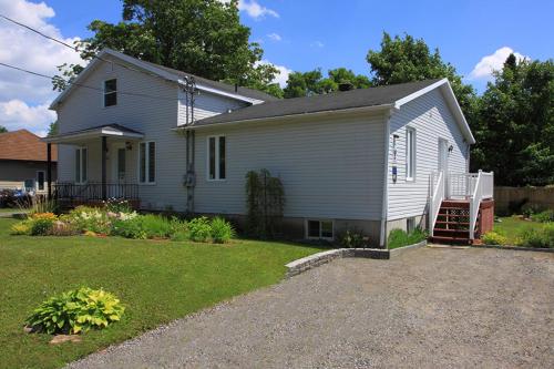 a white house with a porch and a yard at Gite Confort in Quebec City