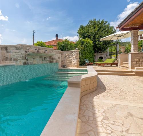 einen Pool im Hinterhof mit einer Steinmauer in der Unterkunft 4 bedrooms seafront Villa LAURUS with heated pool for up to 8 people in Sumartin