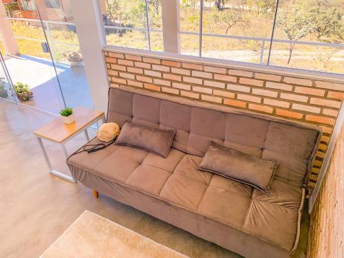 a couch in a living room with a brick wall at Villa Candombá in Alto Paraíso de Goiás
