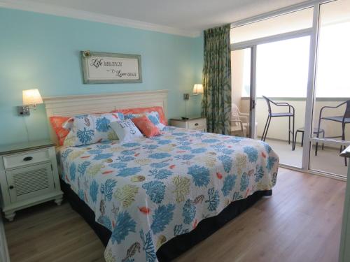 a bedroom with a bed with a colorful comforter at 2 Story Direct Oceanfront Penthouse- Sandy Beach Resort 1116- Sleeps 6! in Myrtle Beach