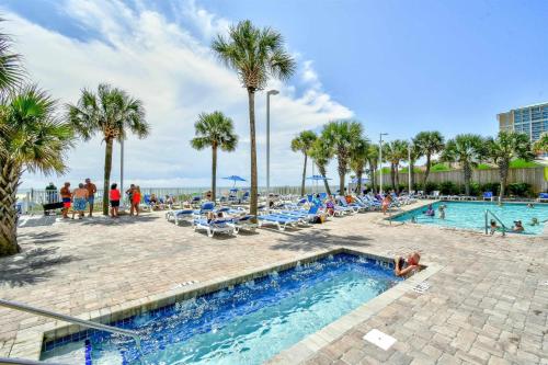 a pool at a resort with palm trees and people at 2 Story Direct Oceanfront Penthouse- Sandy Beach Resort 1116- Sleeps 6! in Myrtle Beach