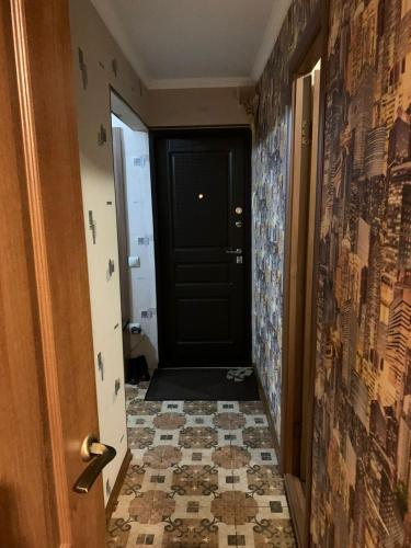 pasillo con puerta negra y suelo de baldosa en 2-квартира Арбат Панфилова 32, en Almaty