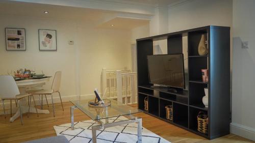 a living room with a tv and a glass table at Modern & Spacious Leeds City Centre Apartment with Parking - Sleeps 5 in Leeds