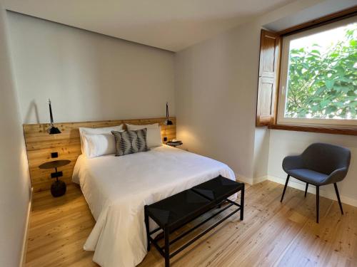 um quarto com uma cama, uma janela e uma cadeira em Santa Clara 1828 em Ponta Delgada