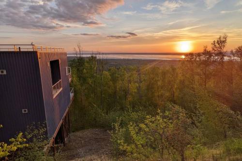 a house with the sunset in the background at Modern 4BR Loft- Denali View, Roofdeck, Pool Table in Eagle River