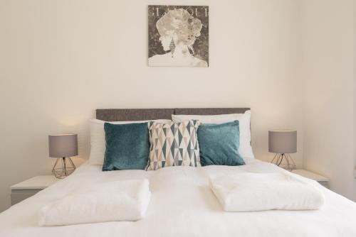 a bedroom with a white bed with blue pillows at Highfield House - 1 Bed-Sleeps 2-TJS20HH in Ilfracombe