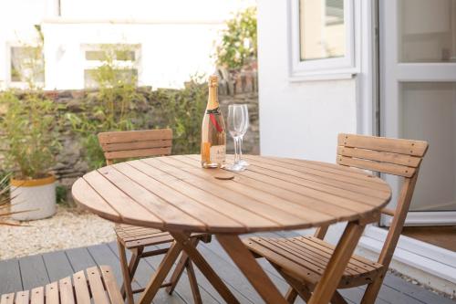 una mesa de madera con una botella de vino y 2 sillas en Highfield House - 1 Bed-Sleeps 2-TJS20HH, en Ilfracombe
