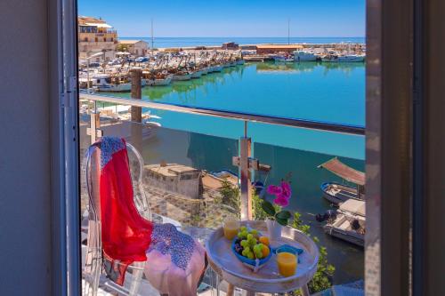 a view of a harbor from a balcony with a table with fruit at Vittoria Luxury Rooms in Sciacca