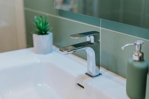 a bathroom sink with a faucet and a plant on it at Mimì Room in Castellammare di Stabia