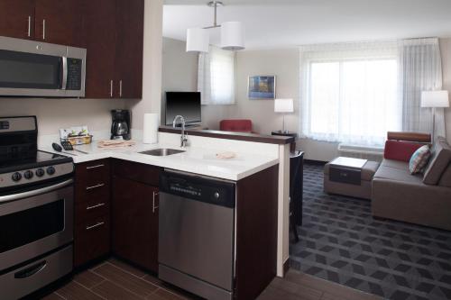 a kitchen with a sink and a living room at TownePlace Suites by MarriottDetroit Canton in Canton