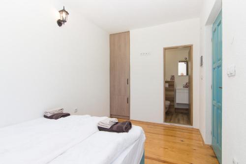 a white bedroom with a bed and a hallway at Retro Village Ravne in Visoko