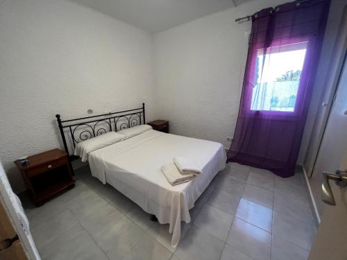 1 dormitorio con cama blanca y ventana en Apartamentos La Isla, en Lloret de Mar