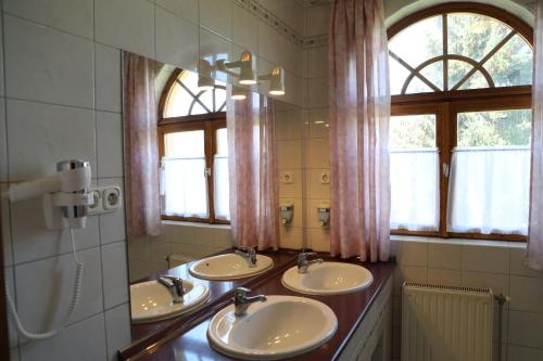 a bathroom with three sinks and two mirrors at Hajdú Kastély Hotel in Hajdúszoboszló