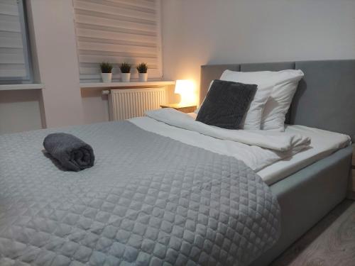 a large bed with a gray blanket and pillows at Apartament River Skierniewice in Skierniewice