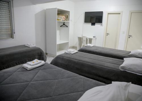 een kamer met drie bedden en handdoeken erop bij Planaltur Hotel in Passo Fundo