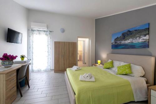ein Schlafzimmer mit einem Bett mit einer grünen Decke und einem Schreibtisch in der Unterkunft Brezza Salina in Torre Nubia