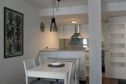 a white kitchen with a white table and chairs at Apartament Ramon a Pobla in La Pobla de Segur