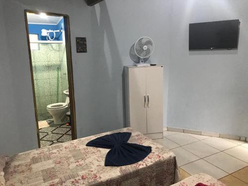 a room with a bed and a refrigerator with a fan at Chalé Raio De Sol in Vale do Capao