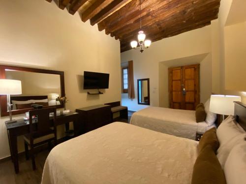 1 dormitorio con 2 camas, escritorio y espejo en Hotel Casa Faroles Centro Histórico en Zacatecas