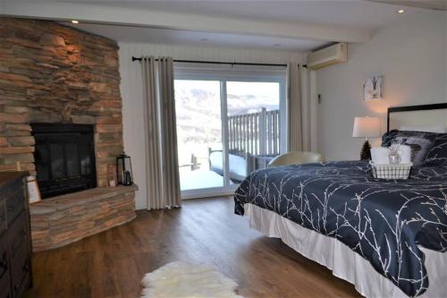 1 dormitorio con 1 cama y chimenea de piedra en Beautiful suite with superb mountain view., en Mont-Tremblant