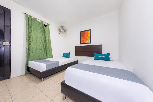 two beds in a room with green curtains at Ayenda Villas de San Juan in Medellín