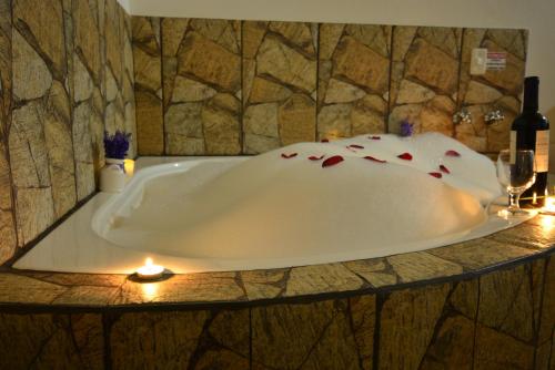 a bathroom with a tub with candles and wine glasses at Pousada Cantinho Colibri in Monte Verde