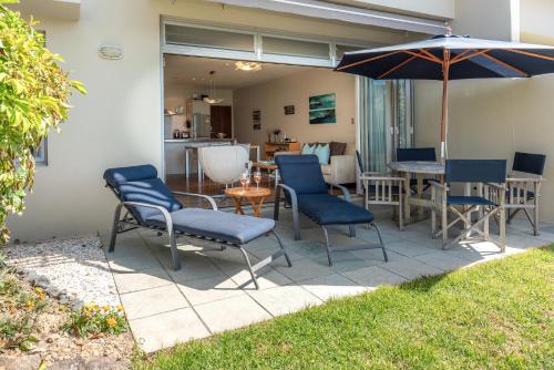 a patio with chairs and a table and an umbrella at The Sands Apartment 23 - Stay Waiheke in Onetangi