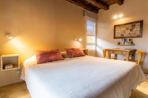 Un dormitorio con una gran cama blanca y una mesa en Suite por los caminos del vino en Mendoza