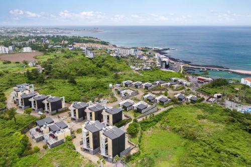 an aerial view of houses on a hill next to the ocean at STANFORD Hotel & Resort Jeju in Jeju