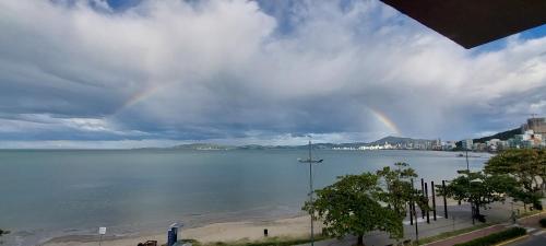 a view of a large body of water with a rainbow at Apartamento de Cobertura frente para o mar Itapema in Itapema