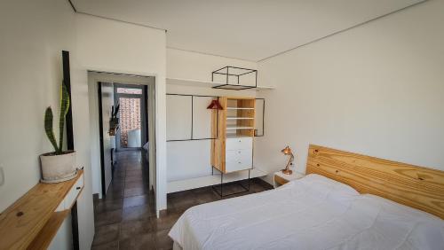 a bedroom with a white bed and a wooden headboard at Casa D, moderna de 2 habitaciones con jardín en barrio de profesionales in San Salvador de Jujuy