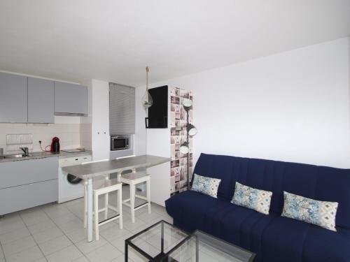 un salon avec un canapé bleu et une cuisine dans l'établissement Charmant T2 à Banyuls-sur-Mer avec jardinet, parking, et proche plage - FR-1-309-260, à Banyuls-sur-Mer