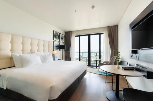 a hotel room with a large bed and a desk at Hotel Soleil Ha Long, Trademark Collection by Wyndham in Ha Long