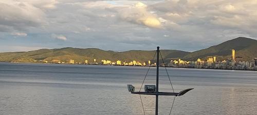 a sail boat in the water with a city in the background at Apartamento de Cobertura frente para o mar Itapema in Itapema
