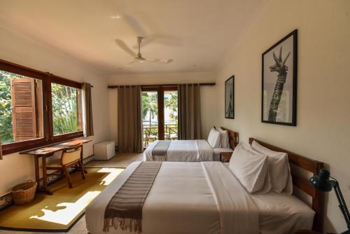 a hotel room with two beds and a desk at Oh Battambang Boutique Hotel in Battambang