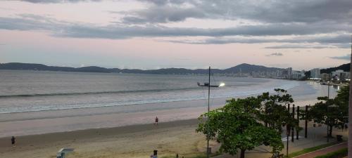 a beach with a person standing on the sand at Apartamento de Cobertura frente para o mar Itapema in Itapema