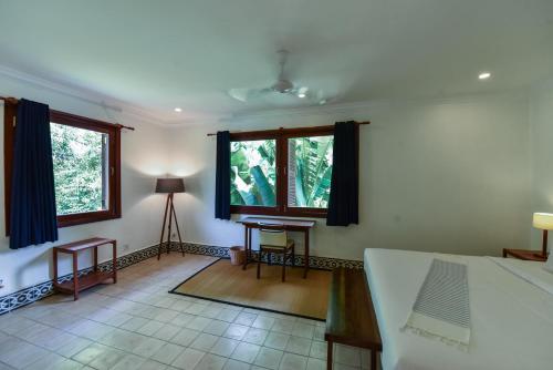 a bedroom with a bed and a table and two windows at Oh Battambang Boutique Hotel in Battambang