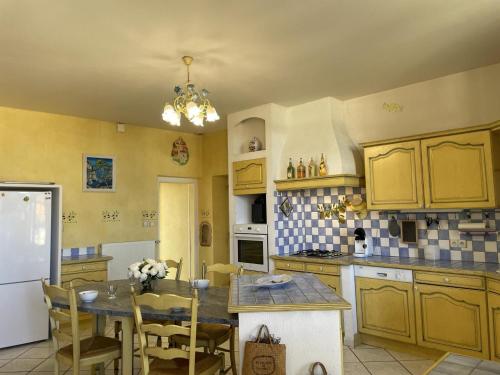 une cuisine avec des armoires jaunes et une table avec des chaises dans l'établissement Maison de famille au cœur du Bourbonnais, 18ème siècle, charme et confort, proche loisirs et commerces - FR-1-489-387, à Pierrefitte-sur-Loire