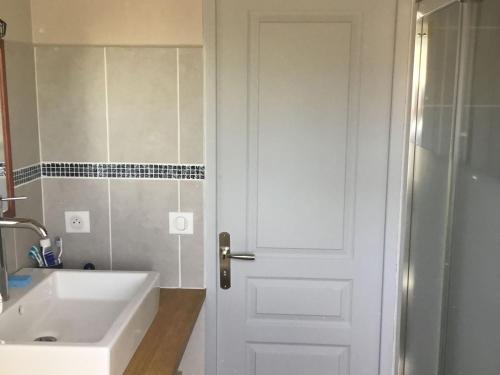 La salle de bains est pourvue d'une porte blanche et d'un lavabo. dans l'établissement Maison cosy à Kervilahouen, 1 km de la mer, jardin, terrasse, BBQ, proche supérette, 5 pers. - FR-1-418-192, à Bangor