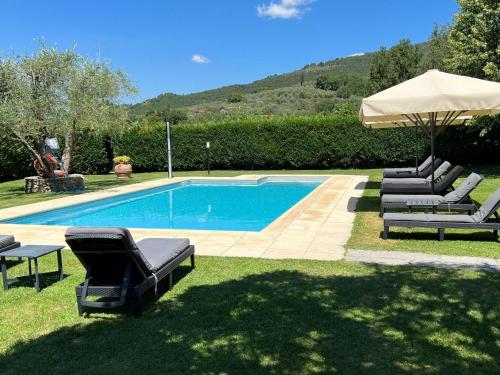 una piscina con tumbonas y sombrilla en Belvilla by OYO Villa a Loro Ciuffenna, en Loro Ciuffenna