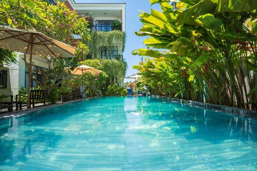 a large blue swimming pool in a building with plants at Coco Island Villa in Hoi An