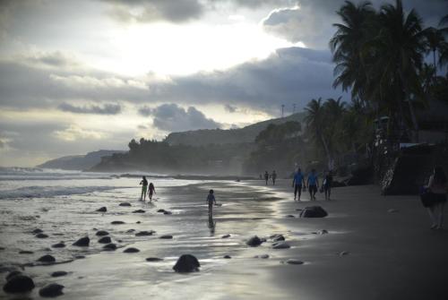 un grupo de personas caminando por la playa en RocaSol Casa d´Mar en El Zonte