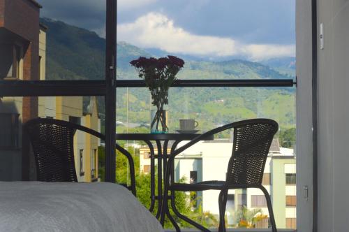 a table with two chairs and a vase of flowers on a balcony at Apartamento con vista y ubicación privilegiada in Armenia