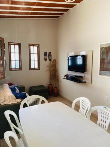 a living room with a white table and chairs and a tv at MAR DOCE LAR - Praia de Sossego in Sao Francisco do Itabapoana